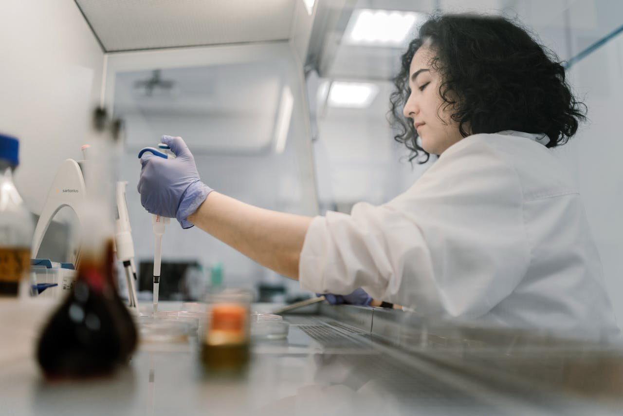 Woman in lab coat conducting research with pipette in modern laboratory.